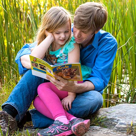 Father reading Ranger Rick magazine to daughter