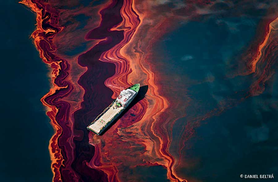 A ship drifts amidst a heavy band of oil spilled in the Gulf of Mexico from the Deepwater Horizon wellhead
